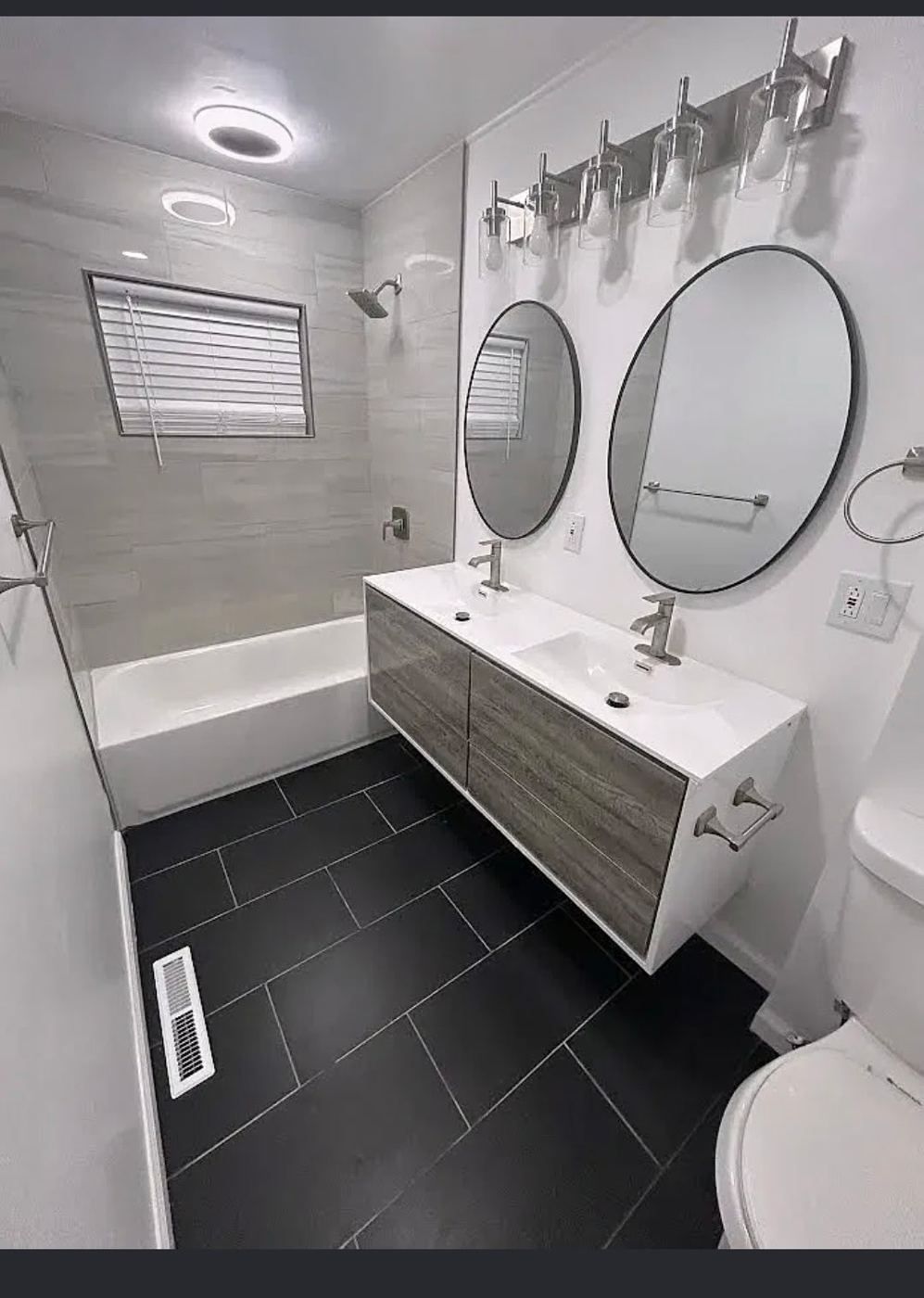 Main bathroom with a double vanity, round mirrors and a tub