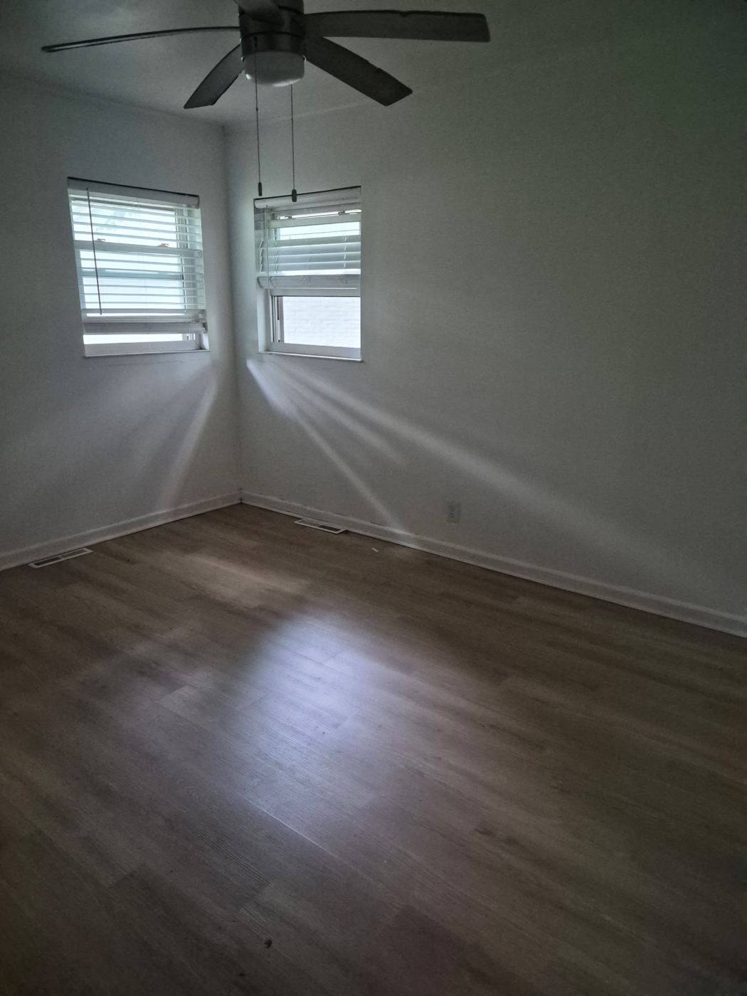 Bright empty bedroom with wood floors and a ceiling fan