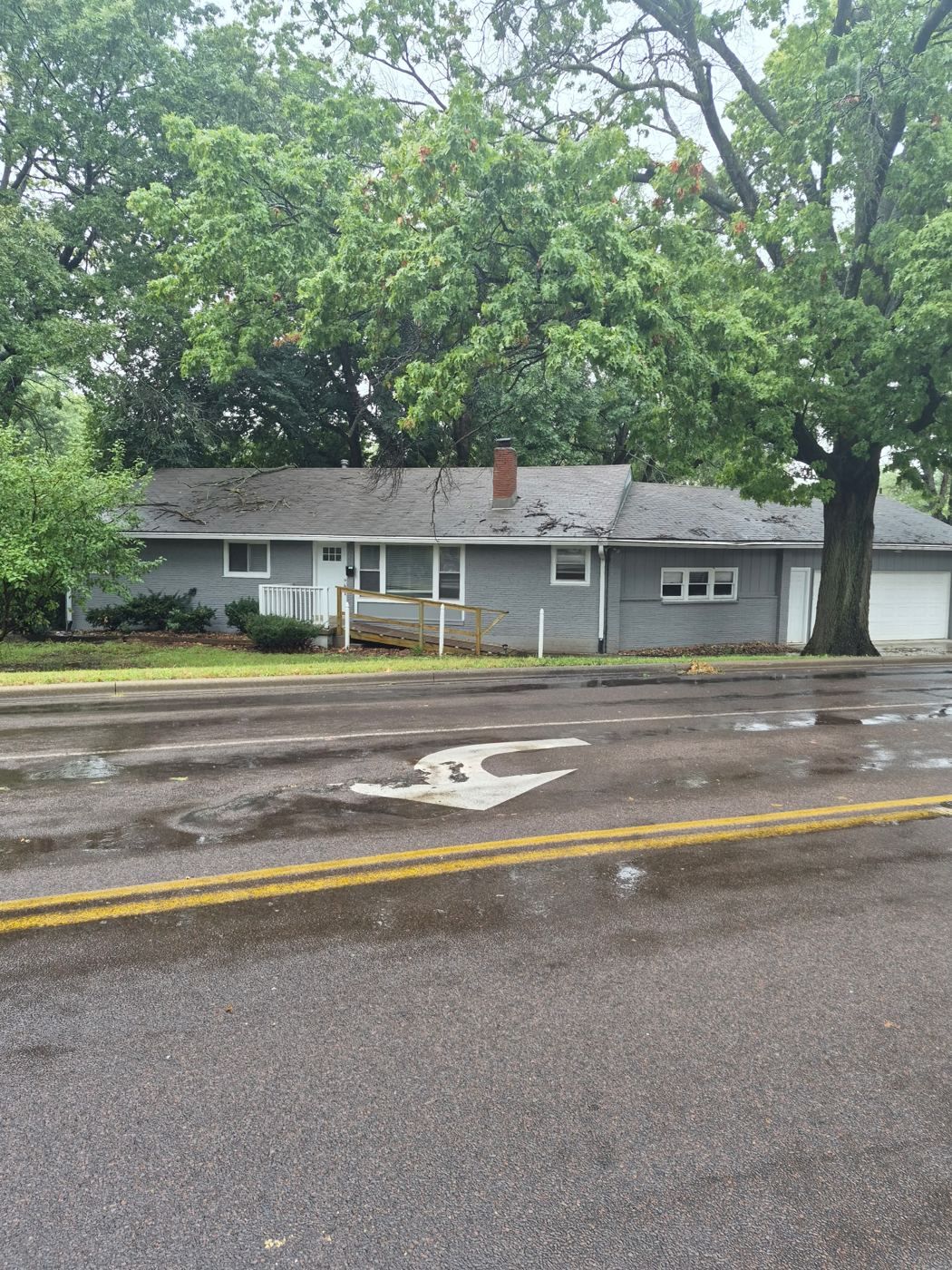 The Changing Generations house: a gray single-story home with a wheelchair ramp to the front door, under mature trees